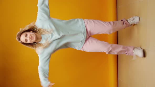 Vertical Video of a Woman Dancer Moving Against Yellow Background in Studio