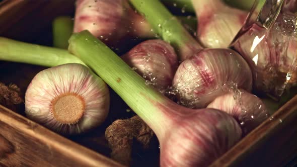 Super Slow Motion on Garlic Pours Water on a Wooden Background