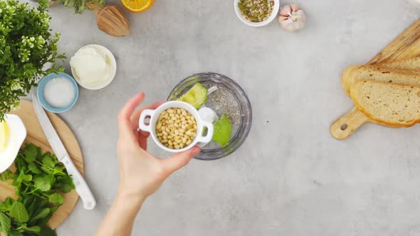 Crop woman preparing cashew avocado dip in blender