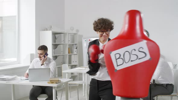 Curly Businesswoman Punching Red Boss Dummy