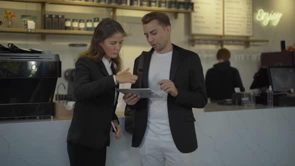 Busy Businssman and Businesswoman Discussing Internet News As Smiling Bartender Giving Them Takeaway