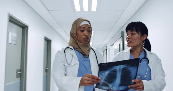 Two female doctors walking in corridor holding x-ray 4k
