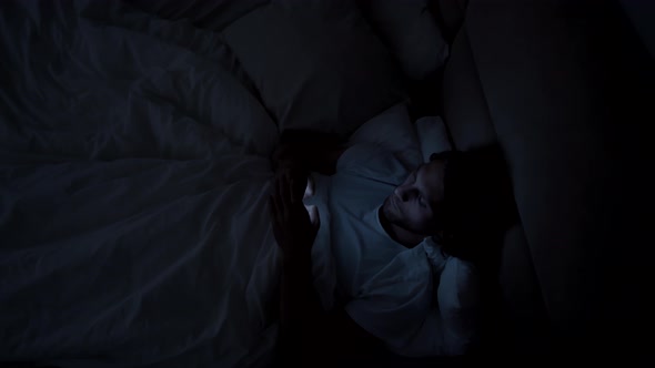 Top View of Man Using Phone in Bed at Night