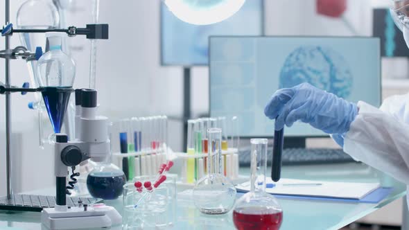 In High End Laboratory Scientist in Coverall Is Taking Sample From Tubes alt