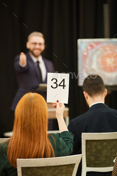 her sign and man pointing at her during auction