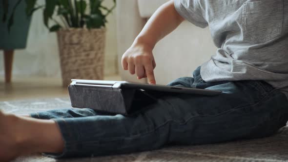 Child Using Tablet Sitting on the Floor at Home Entertainment and Playing Online Games