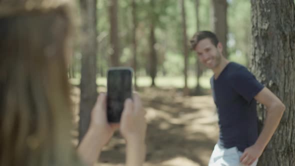 Woman photographing man using smartphone