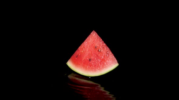 Close up shot of Half Watermelon Rotating on black water surface.Professional studio shot