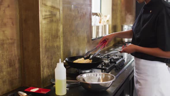 Mixed race female chef preparing a dish and smiling in a kitchen