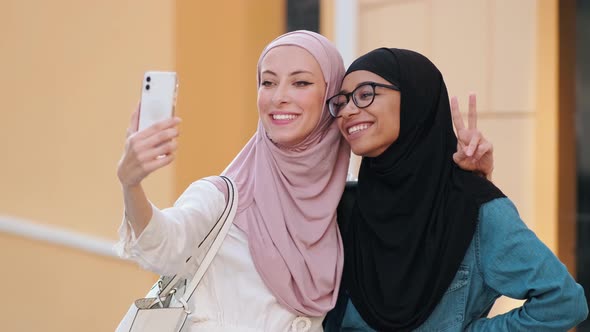 Positive smiling arabian women wearing national hijab is taking selfie photo