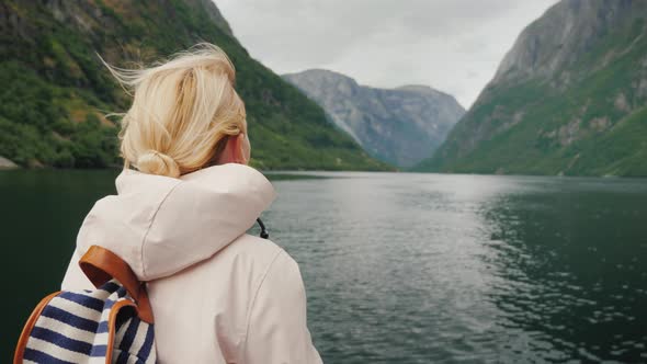 Woman on the Bow of a Cruise Ship Admires the Picturesque Fjord in Norway