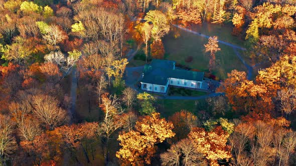 Flight in the evening over trees, park, building. The trees are covered with red, yellow.