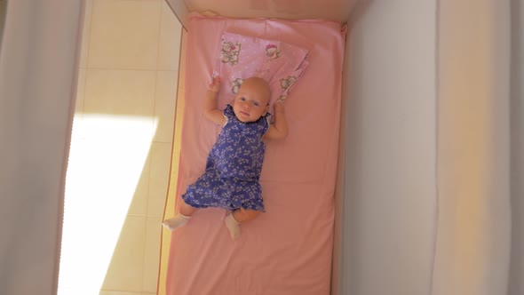 Three months baby girl lying in playpen