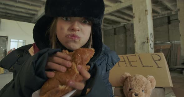Portrait of Ukrainian Refugee with Dirty Face and Grey Eyes Greedily Eating the Bun