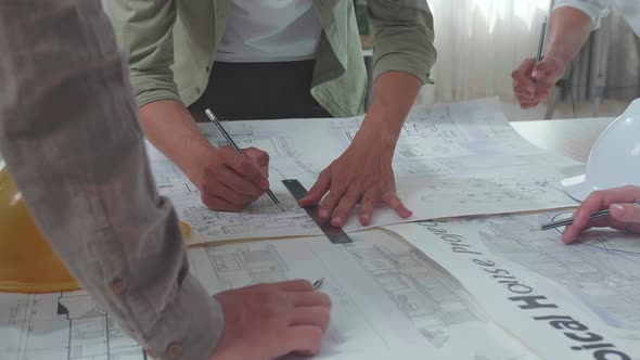 Close Up Of Group Of Asian Engineers Helping Each Other Drawing Building Construction At The Office