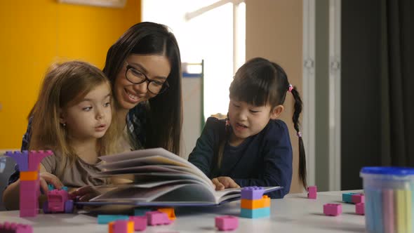 Girls with Teacher Looking at Picture Book at Class