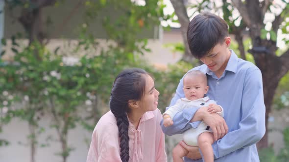 Young Asian family enjoy happiness activity together in garden of their home with morning light