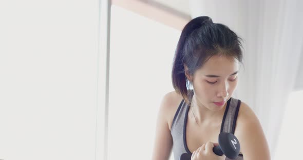 Face close up Asian woman lift dumbbell up for bicep muscle workout