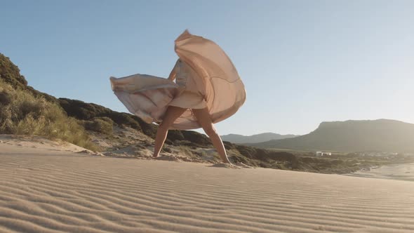 Young Woman Dancing In Long Dress On Sandy Beach