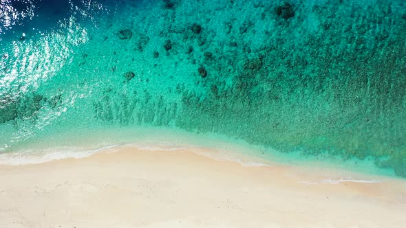 Aerial over a beautiful coral reef in the shallows blue ocean waters of a tropical beach island geta