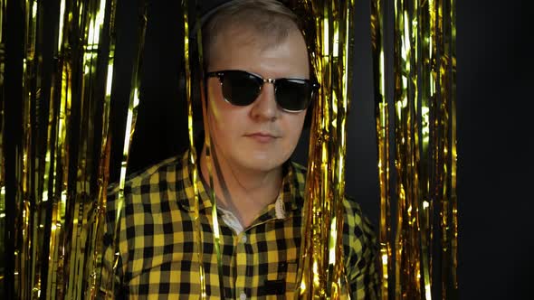Portrait of Caucasian Man Dancing on Black Background. Gold Shining Foil Strips. Party, Music, Disco