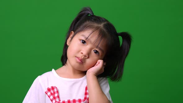 Portrait of happy Asian child girl motion to a camera on green screen background, a child looking at