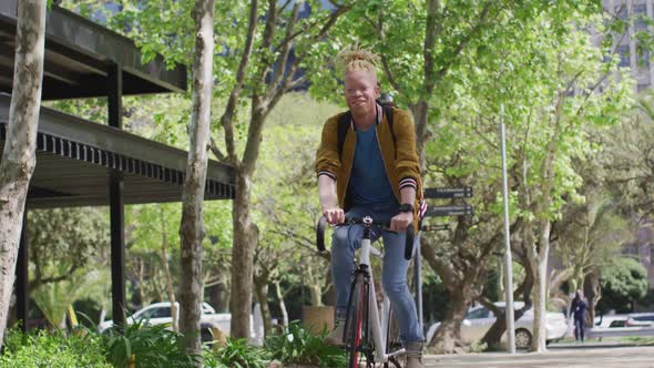 Happy albino african american man with dreadlocks riding bike