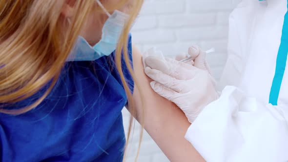 Nurse in Antivirus Suit Giving Vaccine Covid2019 for Teenage Girl