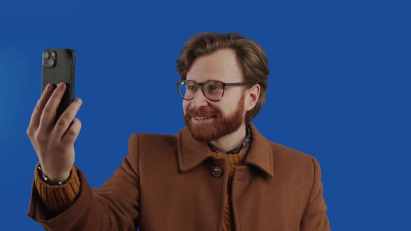 Stylish Red Hair Ginger Bearded Man Talking Over the Smartphone Videocall Blue Screen Chroma Key