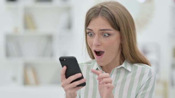 Portrait of Excited Young Woman Celebrating Success on Smartphone 