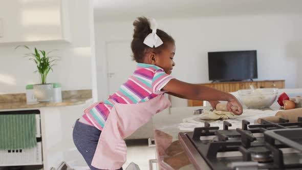 Happy african american girl rolling dough in kitchen