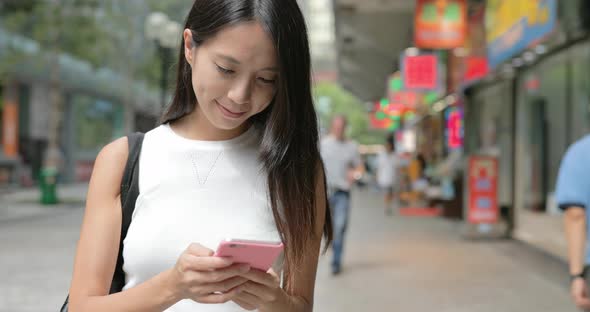 Woman typing on cellphone in city 