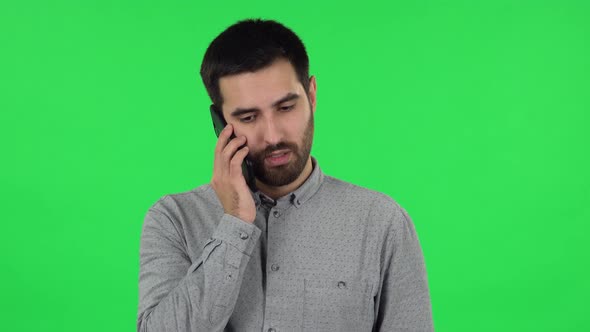 Portrait of Brunette Guy Is Talking for Mobile Phone and Rejoice. Green Screen