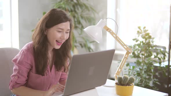 Beautiful Businesswoman Sitting at Her Office Desk Raising Her Arms and Applauds in Celebration of a