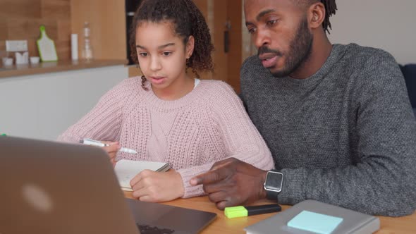 Happy African American Father Helps to Study Online to His Teen Age Daughter