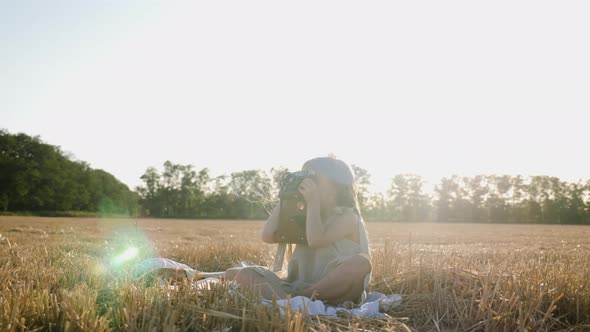 Serious Child Girl with Long Hair Sits on a Mown Wheat Field