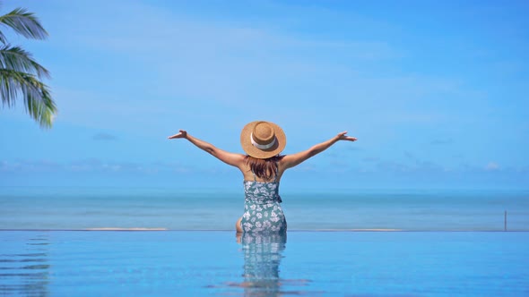 Young woman traveler relaxing and enjoying by a tropical resort pool