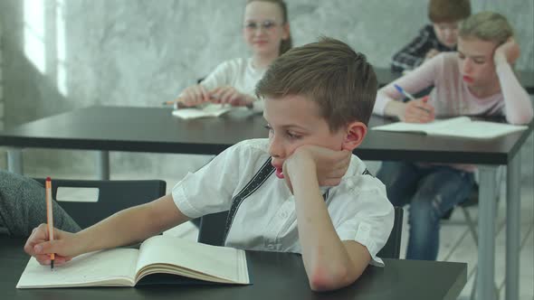 Overworked Young Student Sitting and Listening To a Teacher