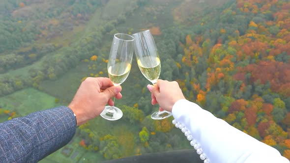 Young Couple Holding Glasses of Champagne in Their Hands on a Background of Autumn Forest Flying on