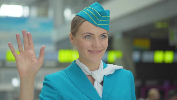 Close-up Portrait of Smiling Beautiful Caucasian Woman in Stewardess Uniform Looking Away and Waving