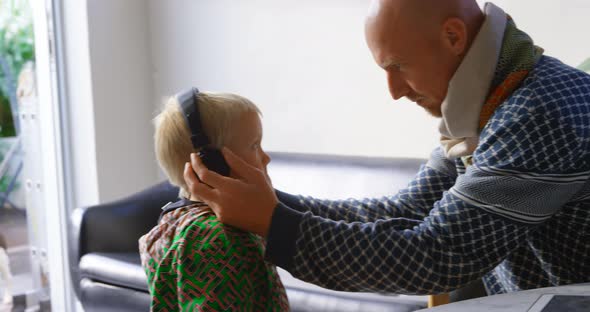 Father and son listening to music on headphones 4k