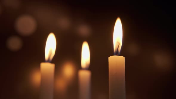 Close Up View of Burning a Three Candles on on a Red Background of Colored Blurred Bokeh