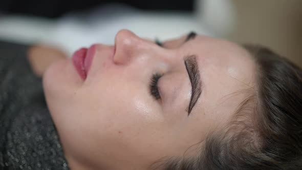 Side View Closeup Face of Young Caucasian Woman in Beauty Salon with Hands of Professional Confident