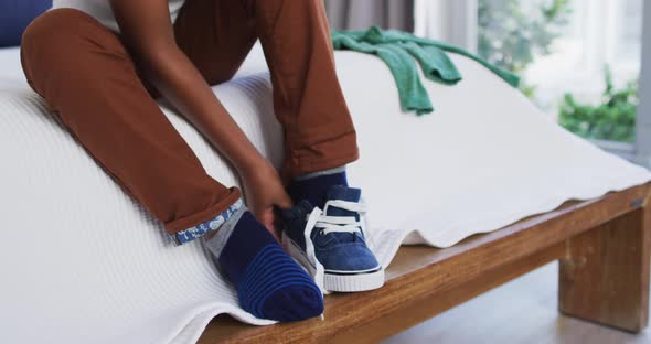 African american boy standing in bedroom getting dressed