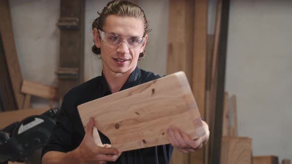 Carpenter Looking at the Edge of a Plank at Workshop