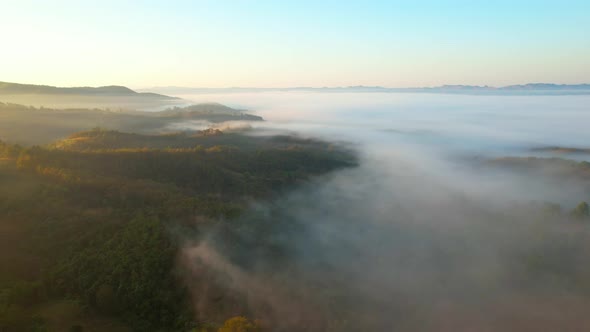 4K aerial view over mountain at sunrise in heavy fog. golden morning sunlight