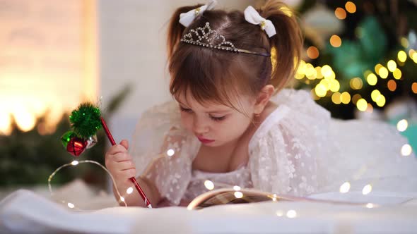 Little Girl Writes a Letter to Santa Claus Under the Christmas Tree