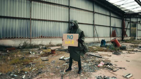 Military Man with Gas Mask and No War Placard in a Nuclear Site Destroyed By War