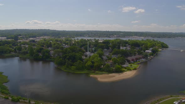 Flying Toward a Small Suburban Town Surrounded by Water on a Sunny Day