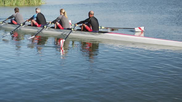 Four senior caucasian men and women rowing boat on a river
